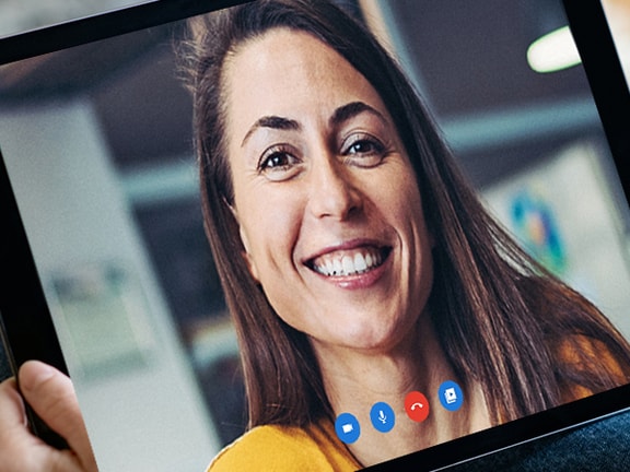 Tablet showing a video call with a smiling woman in a yellow top, using medbridge.