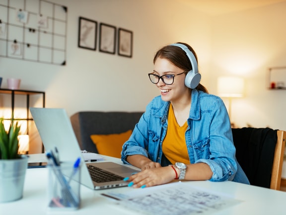 Individual using a laptop with headphones and glasses in a modern, plant-filled room; associated with medbridge.