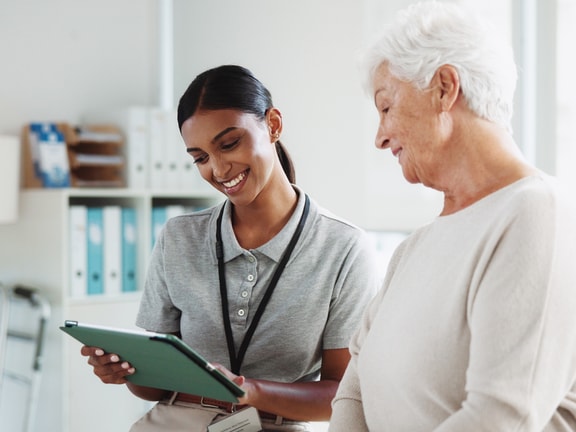 Clinician reviewing remote therapeutic monitoring data with senior patient on tablet
