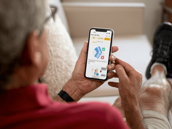 A person sits on a couch using a smartphone to explore medbridge digital healthcare features.