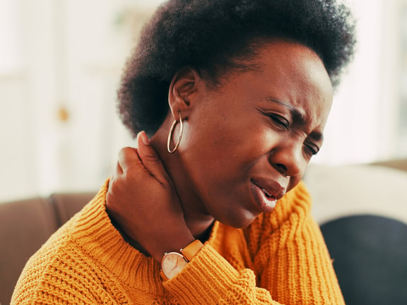 black woman holding neck in pain - neck disability index