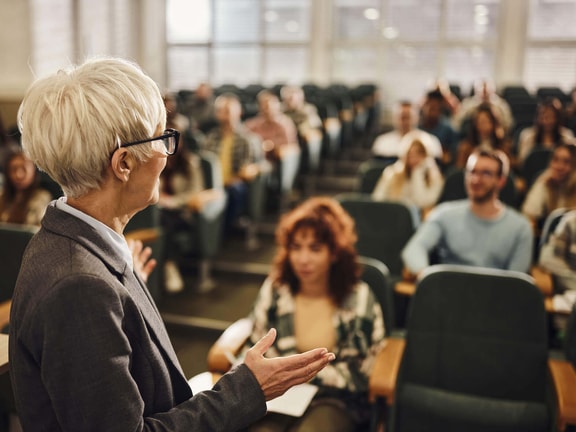 An instructor speaking to a group in a classroom, showing how voice is used in everyday professional work.