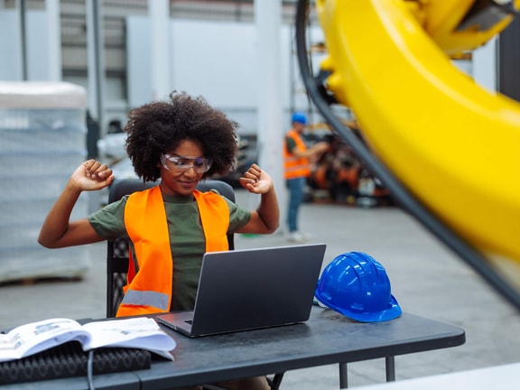 Person wearing safety gear while working on a laptop at a desk. Risk adjustment factor.