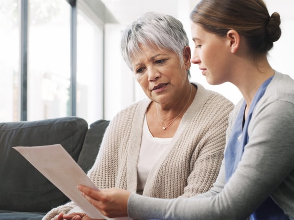 Clinician reviewing a semantic feature analysis worksheet with an older adult during a therapy session at home.