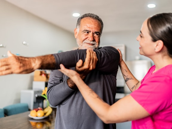 Clinician assisting older adult with shoulder mobility exercise to address anterior shoulder pain.