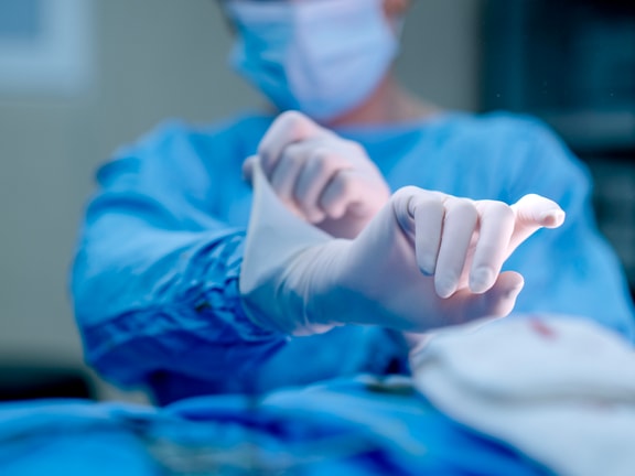 Orthopedic surgeon puts on sterile gloves before an operation in a surgical suite