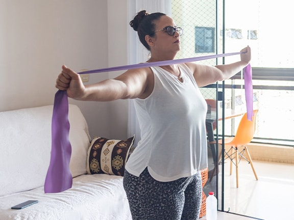 Person using a purple resistance band in a living room, visible on medbridge.