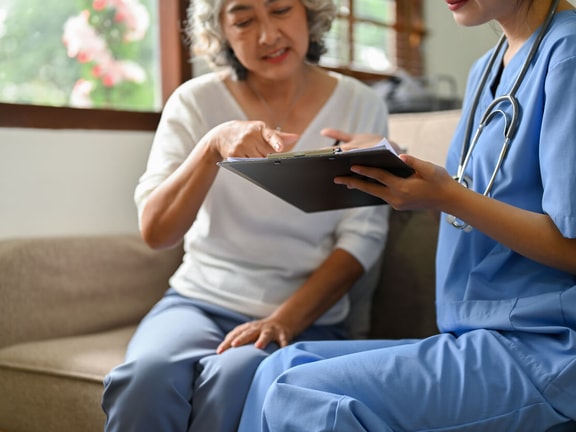 Home health nurse educates patient on using a JP drain color chart for post-surgical drainage monitoring.