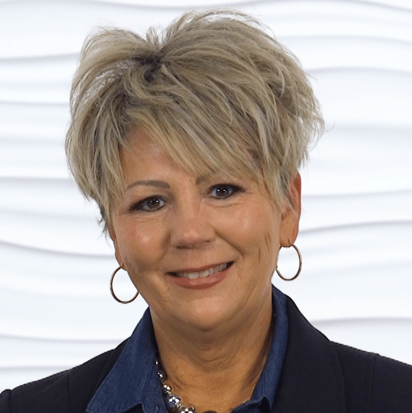 A smiling person in a denim shirt and black blazer represents hybrid care for medbridge.