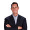 Man in dark blazer and light shirt smiling with arms crossed, against a plain white background, for medbridge.