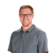 Person smiling in glasses and gray polo shirt, set against a white background, promoting medbridge.