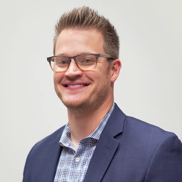 A smiling man with glasses and a blue blazer, suggesting professional charisma in healthcare education, represents medbridge.