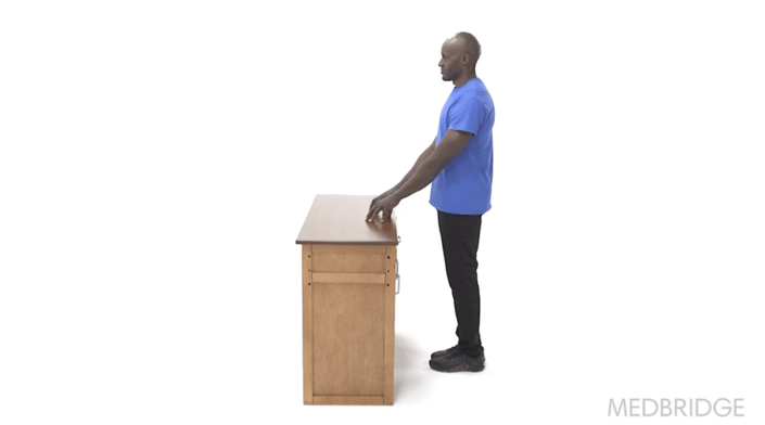 A focused person in a blue shirt engages in digital healthcare training with Medbridge against a white background.