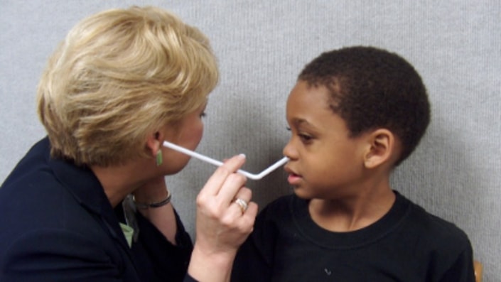 A woman tests a young boy's hearing using digital healthcare tools, depicted on a medbridge platform.