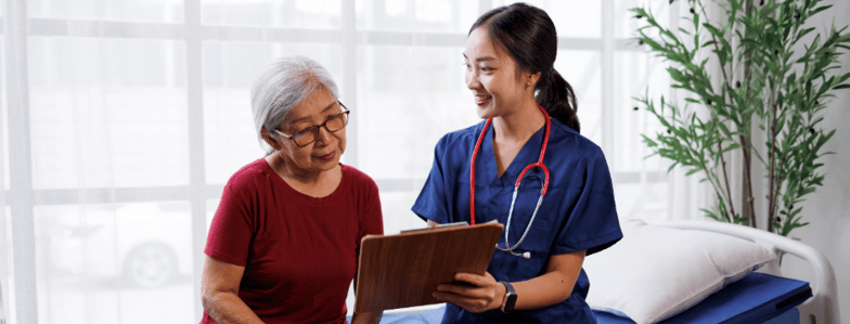 A nurse in blue scrubs discusses a clipboard with an older woman, emphasizing medbridge healthcare education.