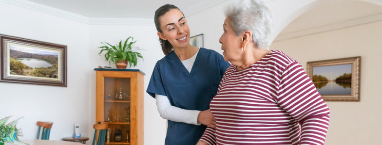 A healthcare worker uses Medbridge software to assist an elderly woman during a home visit.